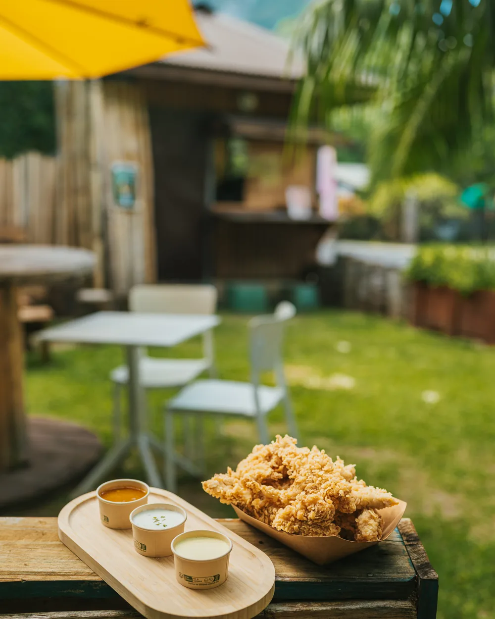 La terrasse de Hello Sunshine à Bora-Bora : tables sous le parasol jaune, le comptoir en bois et le Mont Otemanu en arrière-plan